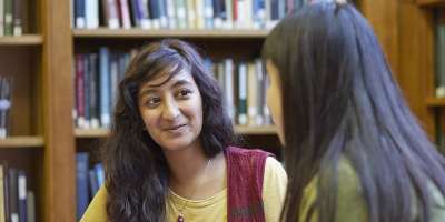 indian student sat in the library talking in discussion with a student