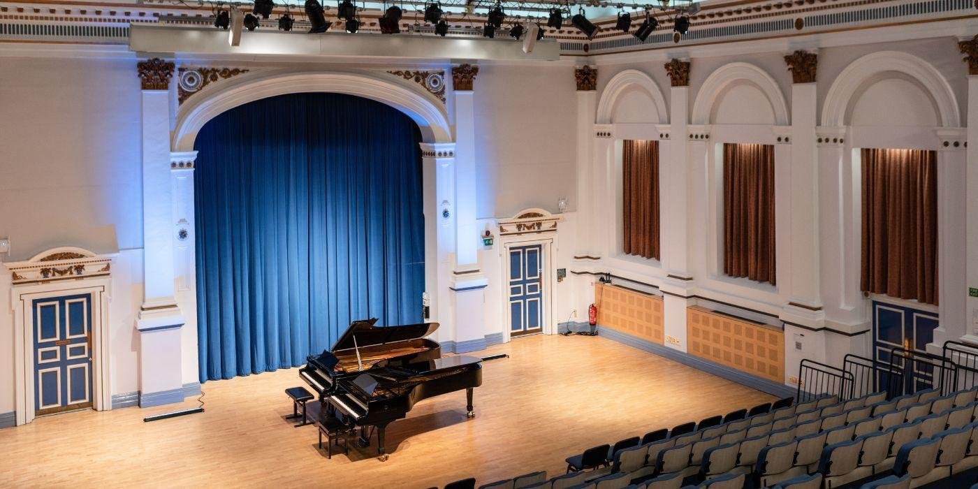 A concert hall with a grand piano on-stage.