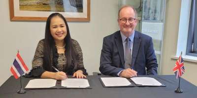 Professor Andrew Thorpe and Dr Orathai Piayura seated at a table, signing the Memorandum of Understanding.