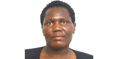 Dr Tendai Mangena portrait. Tendai looks directly at the camera and is smiling, she stands against a white background.