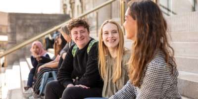 A group of students sat on Parkinson steps talking and smiling