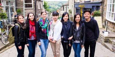 A group of Leeds International Summer School (LISS) student stood on the cobbled road of Haworth main street in Yorkshire
