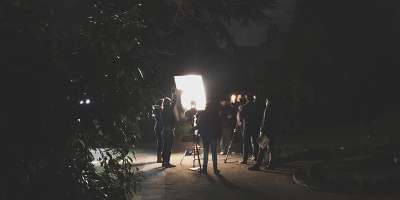 A film crew shooting at night in front of a large spotlight
