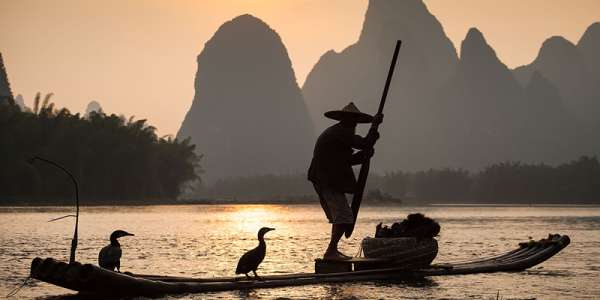 Silhouette of man fishing at sunset