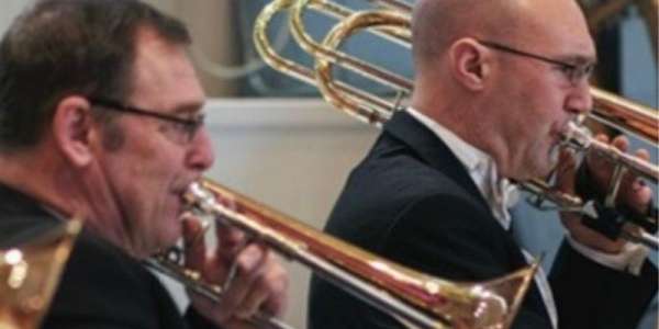 Rob Burtenshaw vocal and instrumental teacher in the School of Music. Rob is playing the trombone and the image is taken side on. Rob is to the left of the frame with a colleague to the right also playing an instrument.